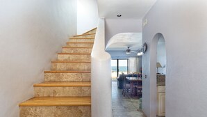 Un escalier en bois mène à une pièce d’où l’on peut admirer la vue sur la mer.