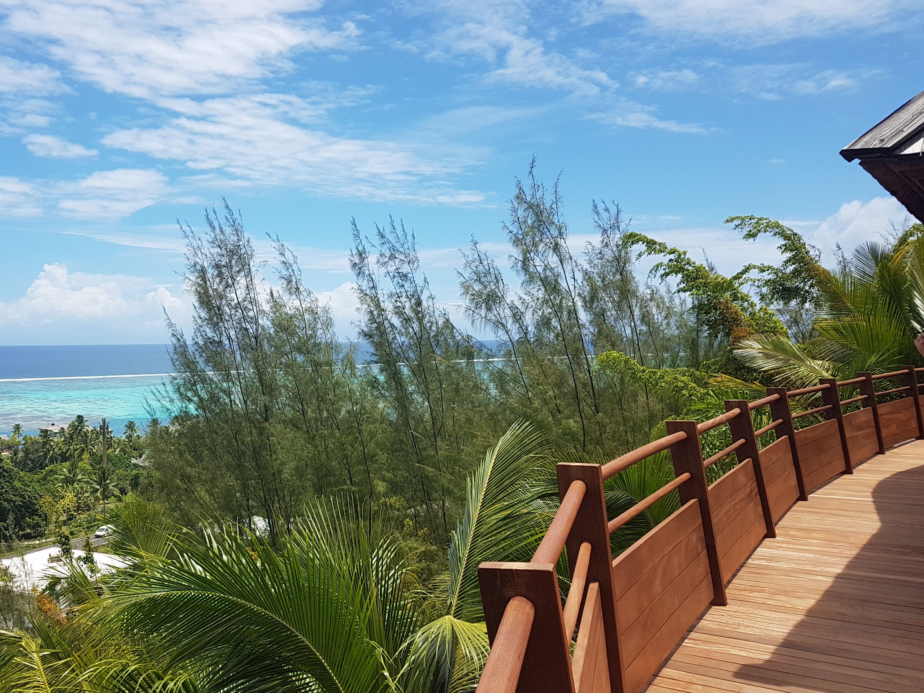 A wooden deck with a railing overlooking a beach and ocean.