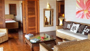 A cozy room with wicker furniture, a glass coffee table, and a large mirror. - Villa Tea by Tahiti Homes (Moorea-Maiao)