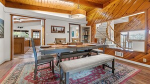 Un vaste espace dédié à la salle à manger, avec un plafond en bois, une grande table, des bancs et un tapis à motifs.