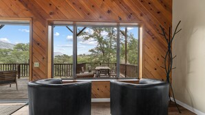 Une pièce dotée d’une grande fenêtre donnant sur une terrasse aménagée avec du mobilier d’extérieur.