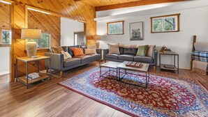 Un salon spacieux avec des poutres apparentes en bois au plafond, une grande moquette et deux canapés.