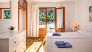 Une chambre à coucher avec un lit, un bureau, une chaise et une vue sur la verdure.