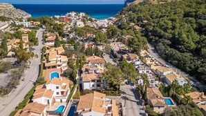 Un quartier résidentiel situé sur la côte, avec des maisons, une route et une vue sur la mer.