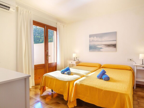 A hotel room with two beds, a painting on the wall, and a view of the outdoors through a door. - Lovely apartment for 8 people with A/C, pool, WIFI, TV and terrace (Pollença)