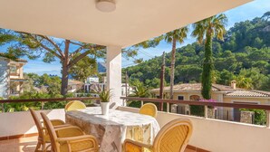 Une terrasse avec une table et des chaises, offrant une vue panoramique sur un paysage verdoyant, avec des arbres et des bâtiments.