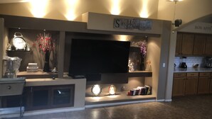 A modern kitchen with a built-in TV, decorative shelves, and a ceiling fan. - VISIT ARIZONA IN STYLE                   ENJOY A HEATED POOL (Goodyear)