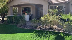 A house with a covered porch, a small garden, and a well-maintained lawn. - VISIT ARIZONA IN STYLE                   ENJOY A HEATED POOL (Goodyear)