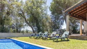 Une piscine avec des chaises longues et une pergola.