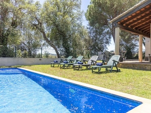 Una piscina con sillones de descanso y una pérgola.
