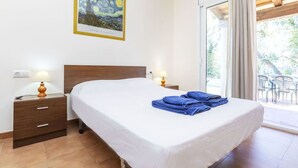 Une chambre d’hôtel avec un lit, deux tables de chevet avec des lampes, une table de nuit, une fenêtre avec des rideaux et un tableau au mur.