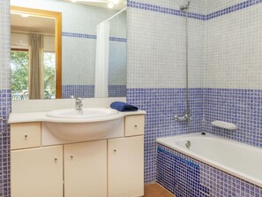 Un baño con lavabo, espejo y bañera.