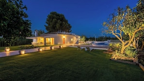 A modern house with a well-maintained lawn, outdoor seating, and a staircase leading to the entrance.