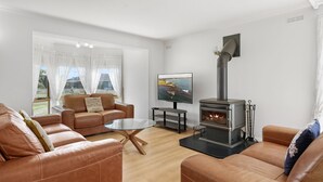 A modern living room with leather sofas, a glass coffee table, a fireplace, and a television.