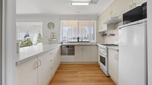 A compact kitchen with white cabinetry, a stainless steel oven, a microwave, and a dishwasher.