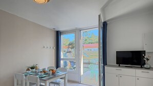 A modern kitchen with a TV, white cabinets, and a dining area with a table and chairs. - Lovely apartment in villa for 4 guests with WIFI, pool, TV, terrace and pets allowed (Saint-hilaire-de-riez)