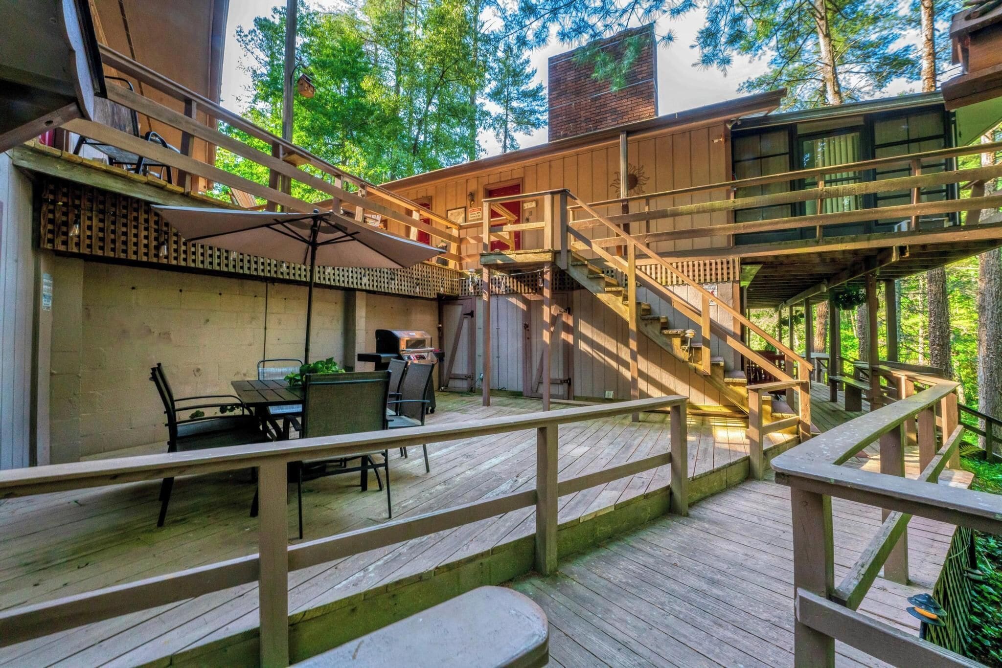 A wooden deck with a staircase leading to a covered area with a table and chairs.