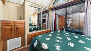 A bedroom with a large bed, wooden cabinets, a mirror, and a sliding glass door leading to a balcony. - The Cascades Inn (Tiger)