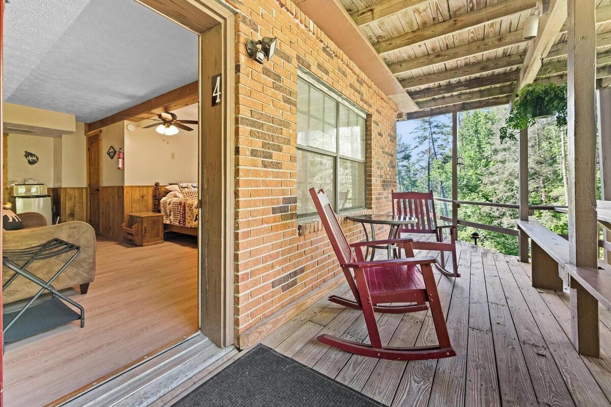 A wooden deck with a brick wall, a rocking chair, and a table.
