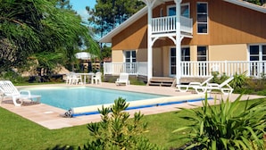 Ein zweistöckiges Haus mit Pool, weißer Gartenmöbeln und einem Balkon.