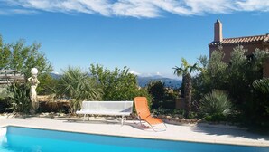 Une piscine avec des chaises longues et une statue.