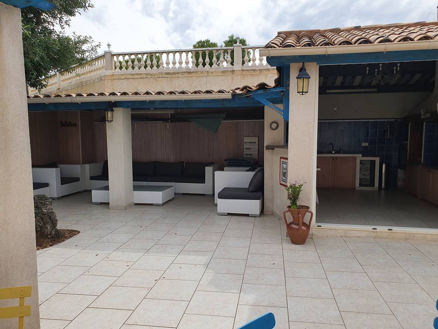 Un espace extérieur aménagé en terrasse, avec des sièges, un pot de fleurs et une vue sur l’immeuble voisin.