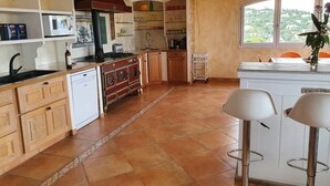 Une cuisine équipée d’une cuisinière, d’un évier et de placards, une fenêtre avec vue et un coin bar avec des tabourets.