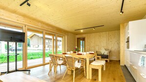 Un intérieur en bois comprenant un coin repas, une cuisine et de grandes fenêtres.