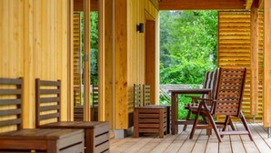 Une terrasse en bois avec une table et des chaises, entourée de murs en bois et offrant une vue sur la verdure.