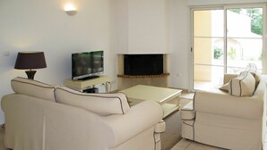 A living room with a sofa, a TV on a stand, a fireplace, and a sliding glass door to the outdoors. - Beautiful apartment in villa for 8 guests with private pool, TV, terrace and pets allowed (Pont-de-larn)