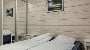 Habitación de hotel con pared de madera, una cama con ropa blanca, dos mesitas de noche y un espejo.