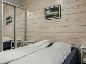 Une chambre d’hôtel avec un mur en bois, un lit avec une literie blanche, deux tables de chevet et un miroir.