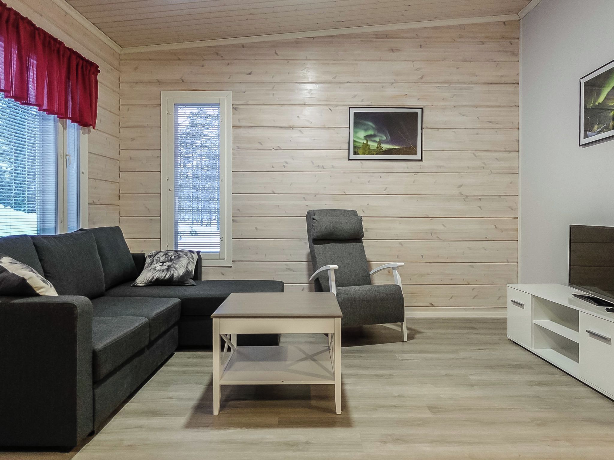 Una sala moderna con un sofá, una silla, una mesita y un mueble para la televisión.