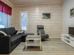 Moderni olohuone, jossa on sohva, nojatuoli, pieni pöytä ja TV-taso.