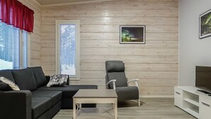 A modern living room with a sofa, a chair, a small table, and a TV stand.