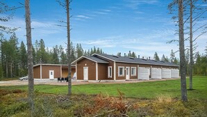 A two-story building with a garage, surrounded by a grassy area and trees.