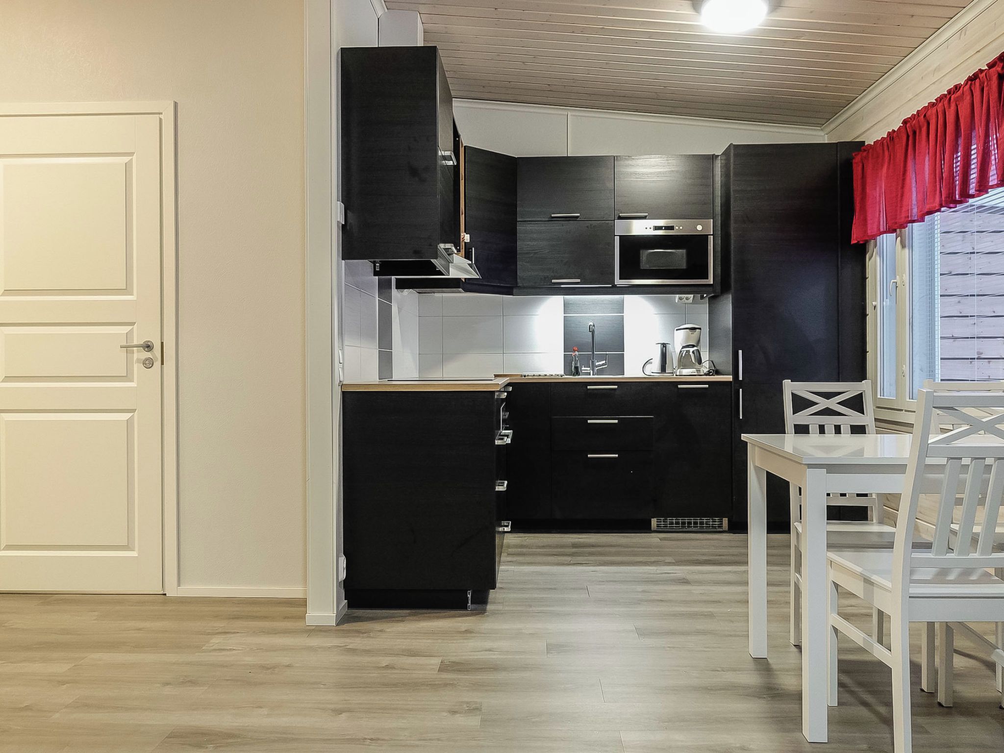Een kleine keuken met een magnetron, oven en moderne kastjes.
