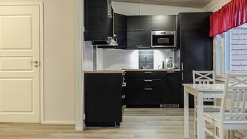 Een kleine keuken met een magnetron, oven en moderne kastjes.