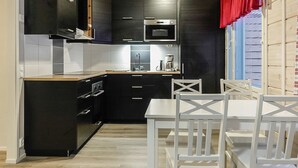 A modern kitchen with black cabinets, a microwave, and a coffee maker. There is a white dining table with chairs.