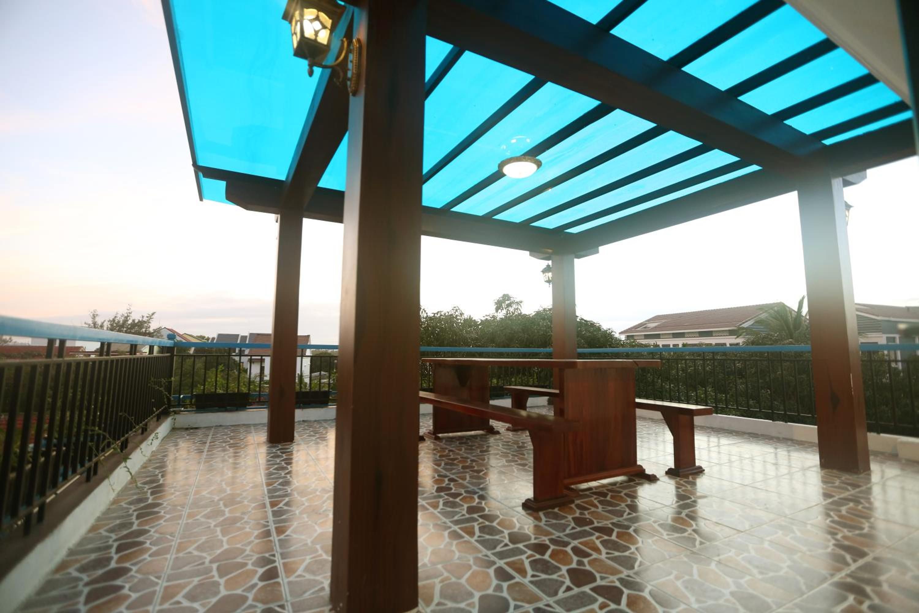 A covered outdoor area with a tiled floor, wooden benches, and a metal railing.