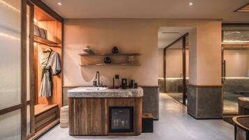 Un baño moderno con tocador de madera, lavamanos integrado y un refrigerador pequeño.