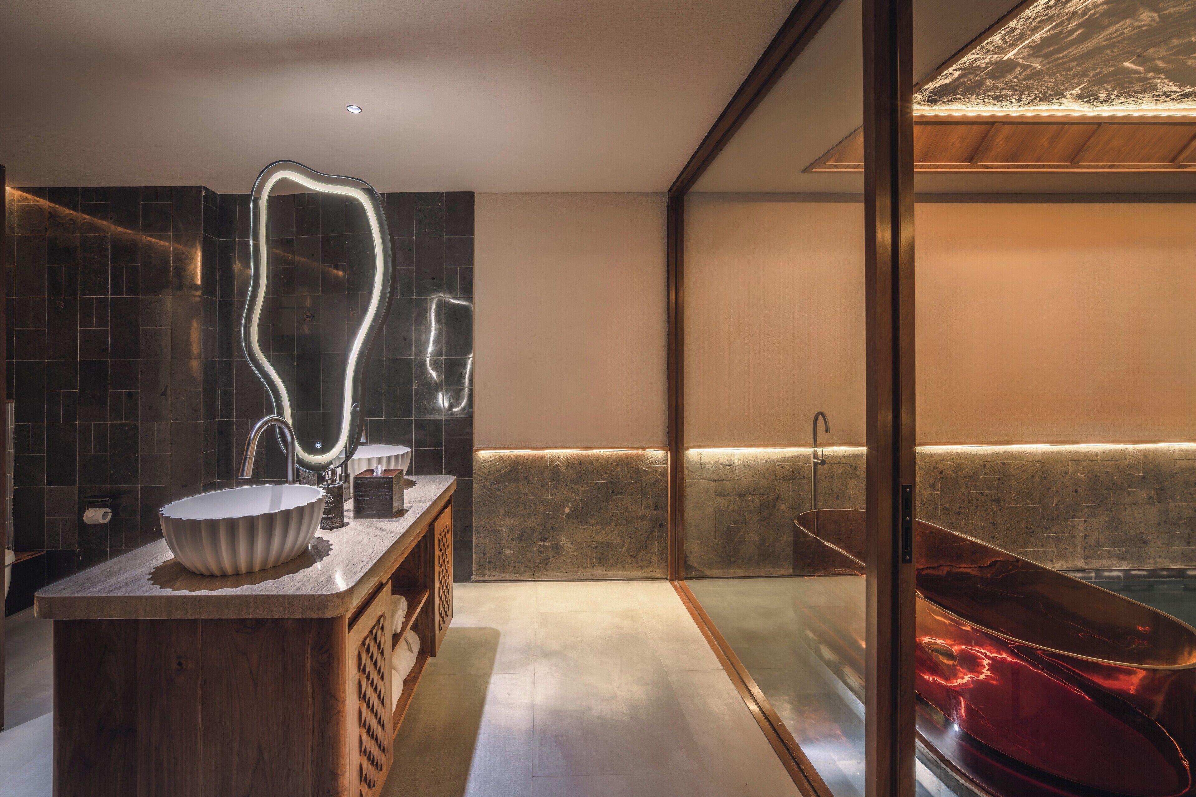 Un baño moderno con tocador de madera, un espejo grande, una bañera y una pared con azulejos.