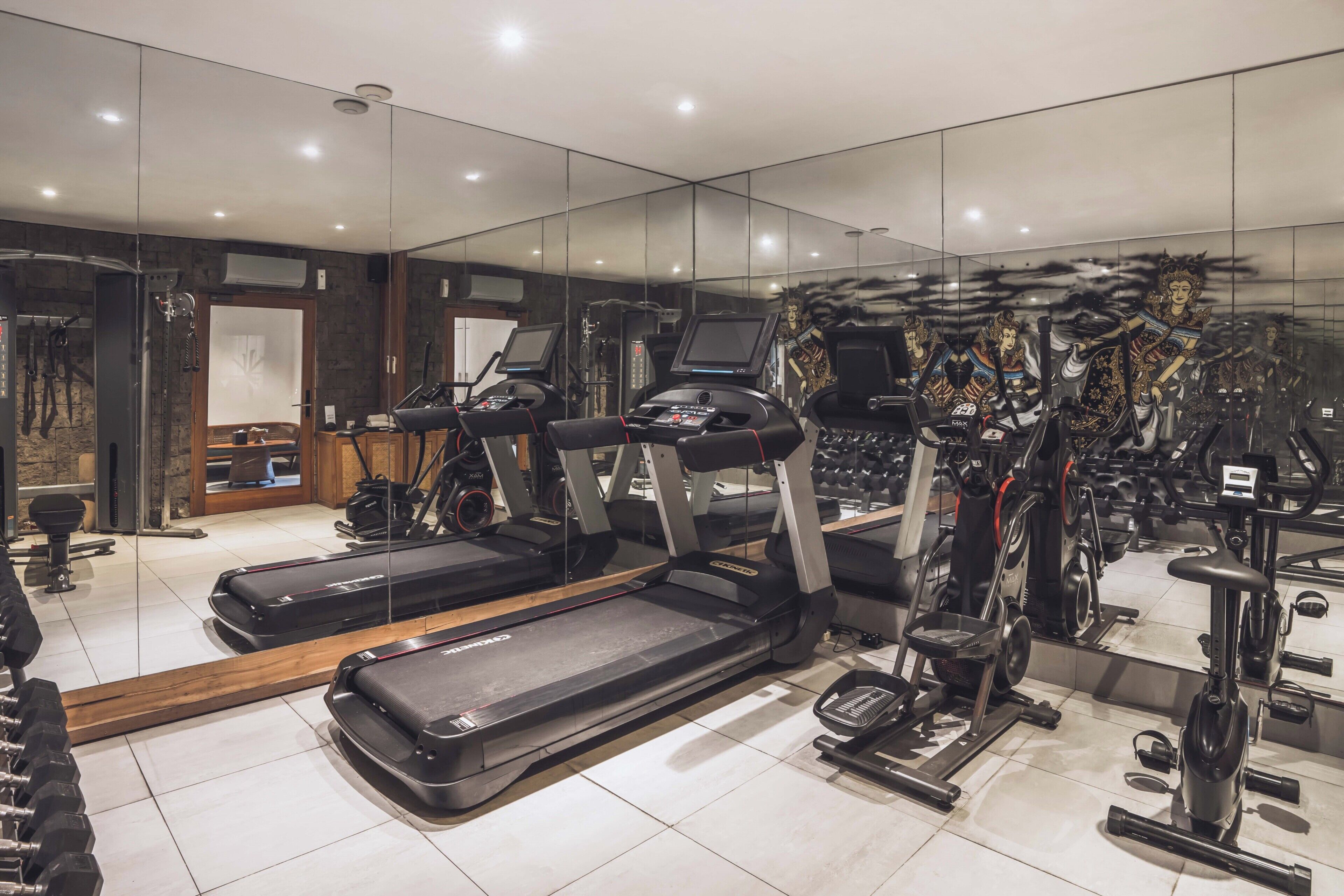 A gym with treadmills, elliptical machines, and weightlifting equipment.