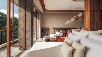 A modern bedroom with a large bed, a sofa, and a dining area.