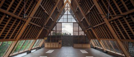 A spacious atrium with a high ceiling, wooden beams, and large windows.