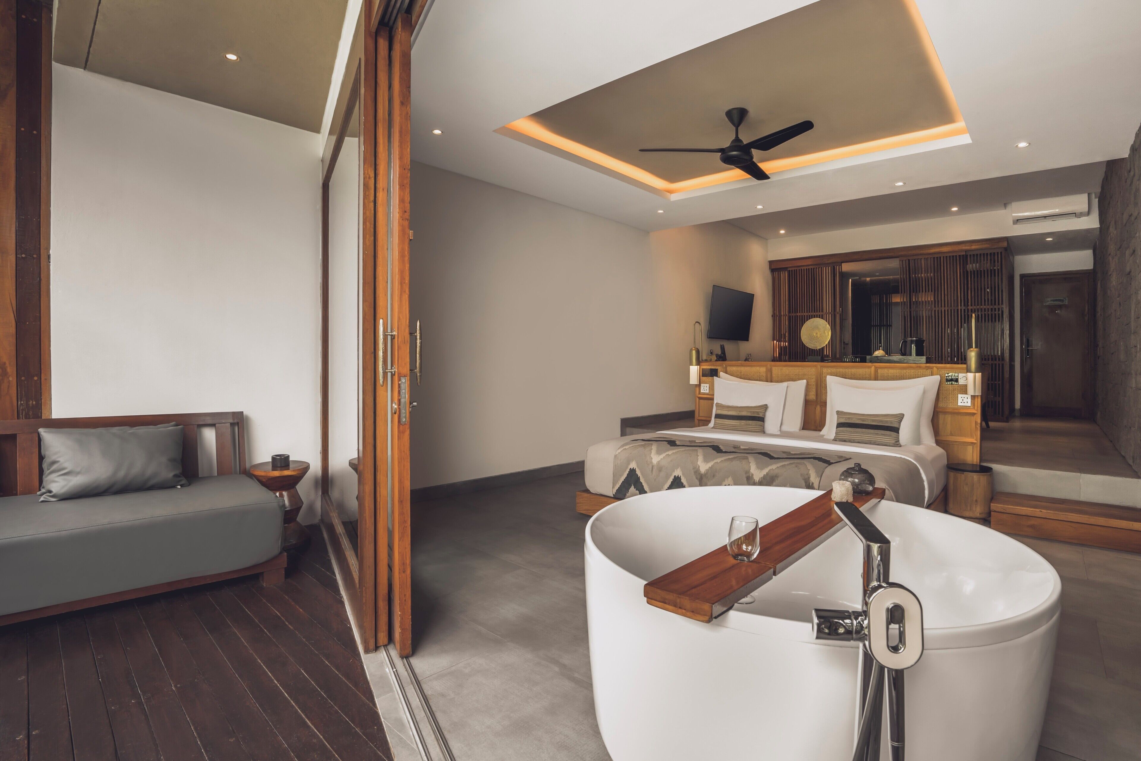 Une chambre à coucher moderne avec une grande baignoire, un canapé et un téléviseur dans un coin.