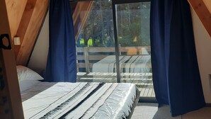 Une chambre à coucher avec un lit, une chaise et une grande fenêtre avec des rideaux.