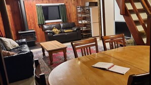 Un salon chaleureux avec une cheminée, un canapé en cuir, une table basse en bois et une table à manger avec des chaises.