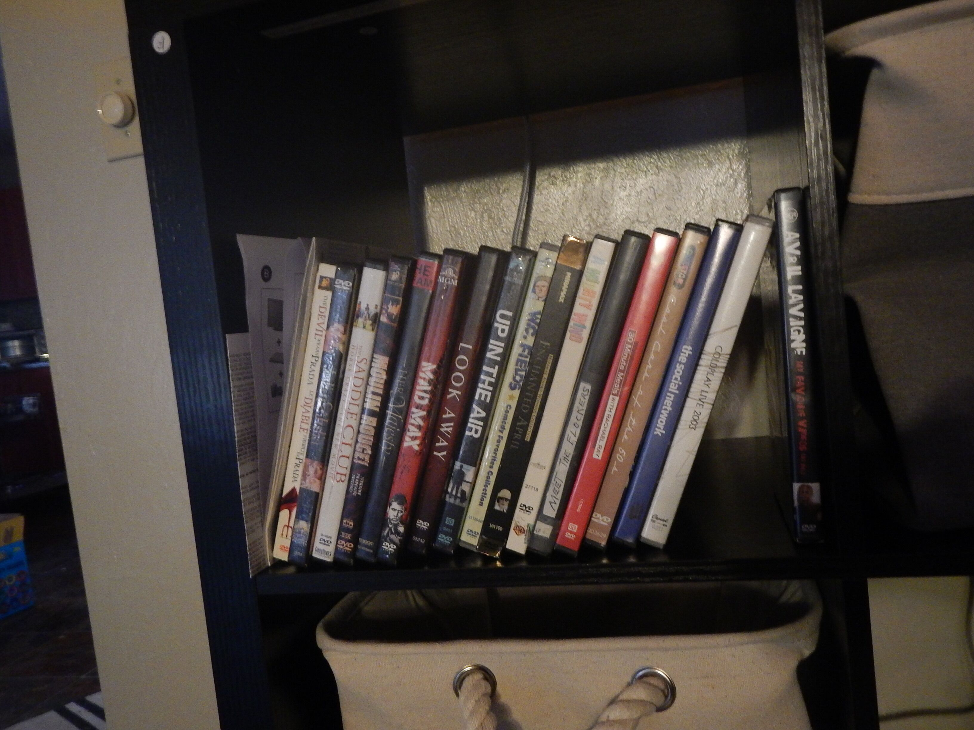 Uma prateleira com DVDs e uma sacola.