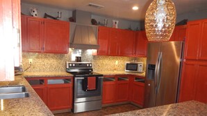 A kitchen with red cabinets, a stainless steel refrigerator, a microwave, and a stove. - Updated Cottage on 6+ wooded acres, Horse setup, RV Hookups, Secluded not remote (Valley Springs)